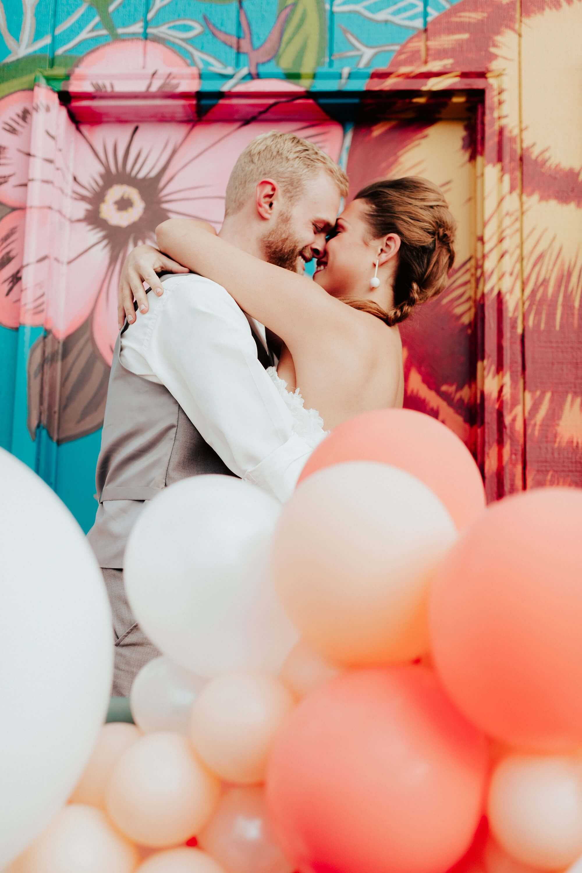 bride and groom kissing by balloons