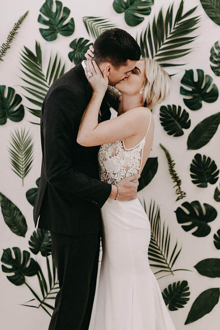 tropical leaf wall bride groom kiss