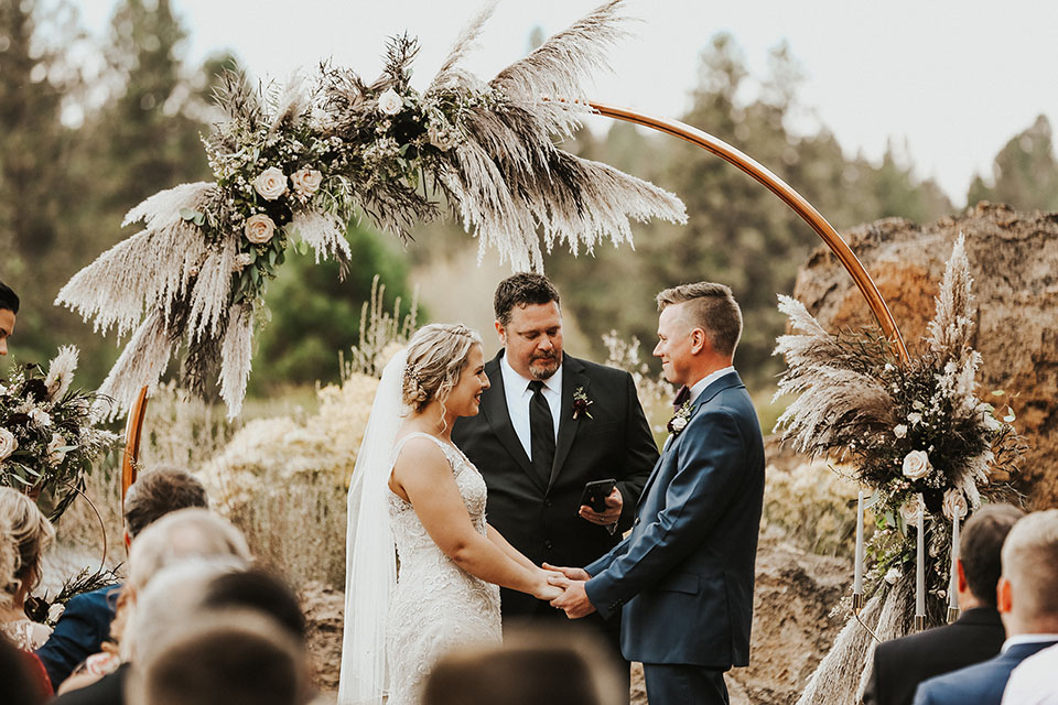bride and groom at ceremony under copper arch