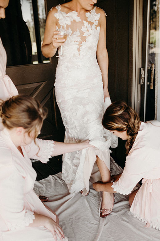 bride putting on shoes with bridesmaids