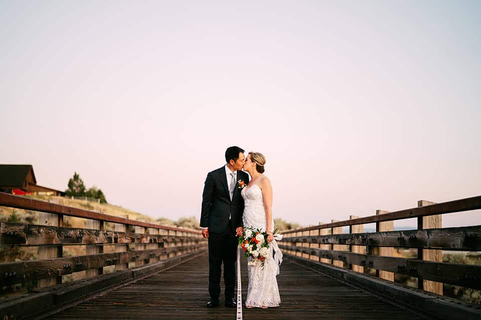 wedding kiss on trestle bridge during sunset