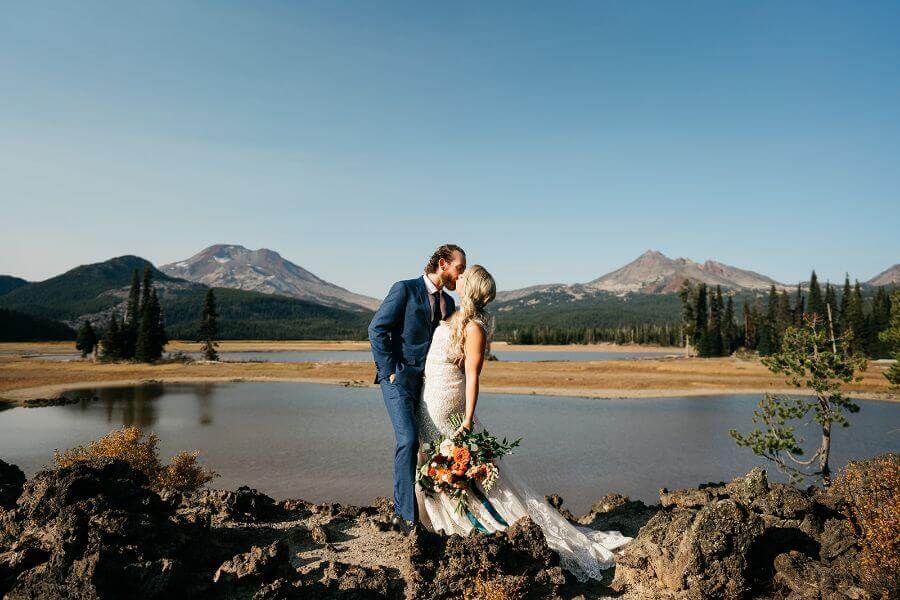 bride and groom next to lake and mountains