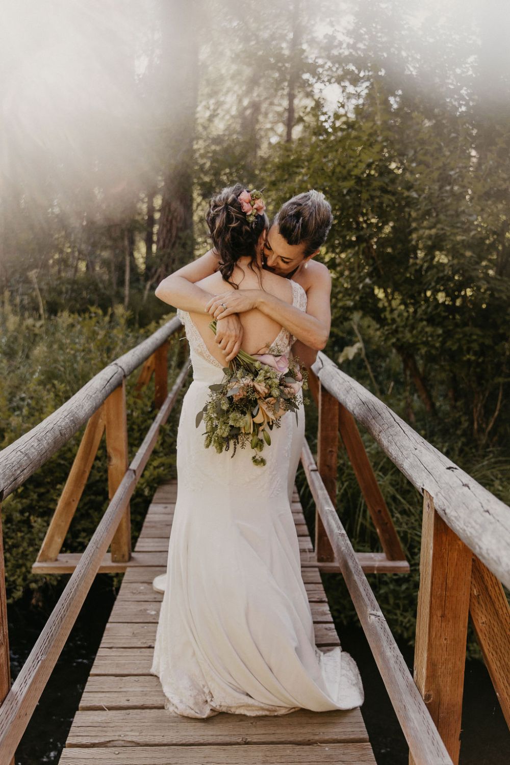 brides hugging on bridge